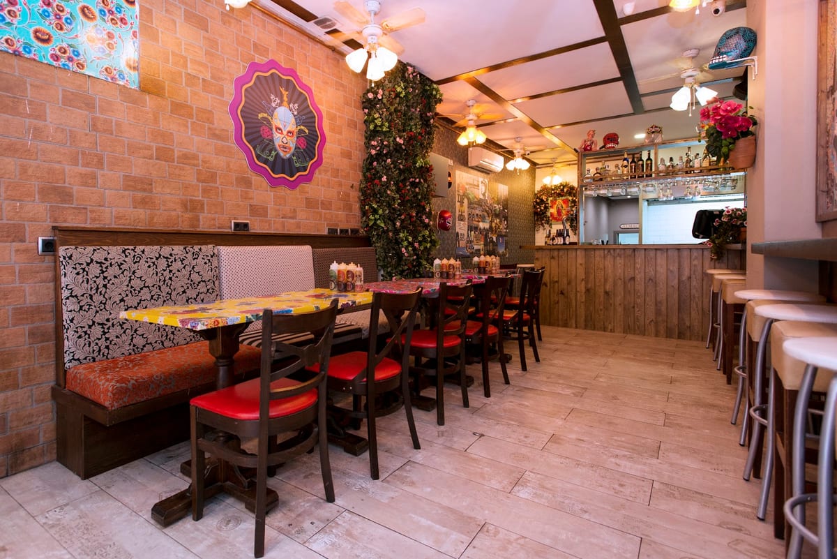 Interior de Chilango's Taqueria en Barcelona con decoración de calaveras y ambiente acogedor, mostrando platos de comida mexicana como tacos — foto oficial del restaurante.